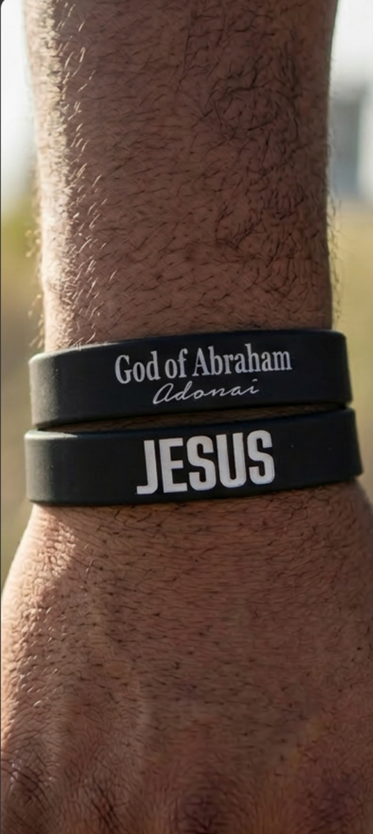 Black wristbands with 'God of Abraham Adonai' and 'Jesus' text on a wrist.