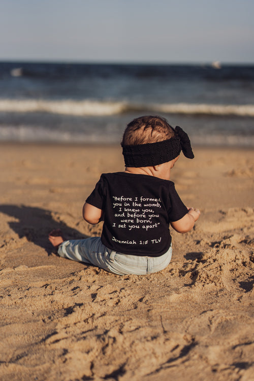 Black organic baby onesie featuring "Before I Formed You" from Jeremiah 1:5, reminding every child they are known by God and created with purpose.