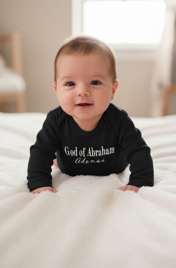 Baby wearing a black onesie with text, lying on a white surface.